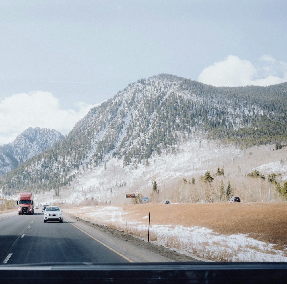 Snow-dusted mountain rising above an interstate highway with a semi truck in the distance